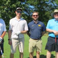 Four golfers with their clubs